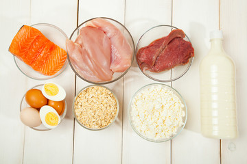 Proteins, fish, cheese, eggs, meat and chicken on a white wooden background