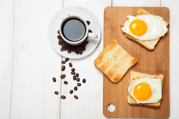 cup of coffee, toast and egg on a white wooden table