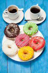 Colorful donuts and two cups of coffee on blue table