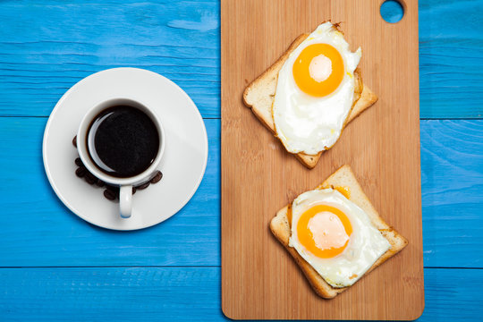 cup with coffee, toast and egg on a blue wooden table