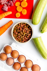 healthy dogfood with eggs, vegetables and meat on kitchen background top view