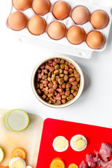 food for pets with meat and eggs on kitchen background top view