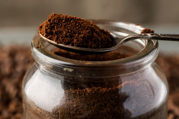 Ground coffee in metal spoon on a glass jar