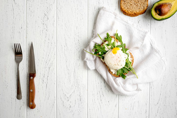 sandwich with poached eggs on wooden background top view