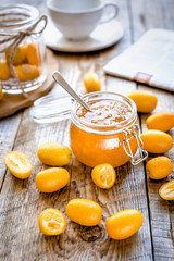 kumquat on plate and jam in jar at wooden table