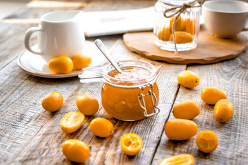 kumquat on plate and jam in jar at wooden table