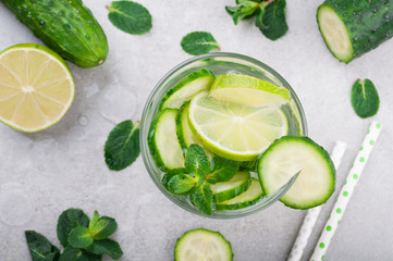 Refreshing water with cucumber, mint and lime on grey background top view. Summer cocktail cucumber lemonade. Healthy drink and detox concept