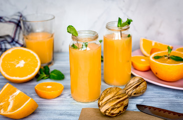 healthy orange cocktail with mint leaves in bottle on kitchen background