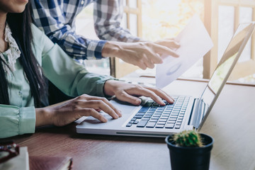 Two colleagues discussing data with new modern computer laptop on desk table. Close up business team analysis and strategy concept.