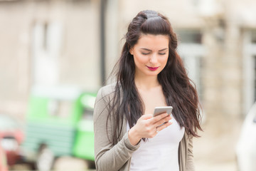 Fototapeta premium Cute girl using cellphone on the street.