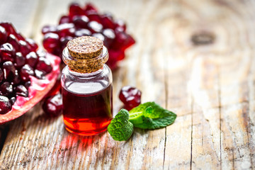 sliced pomegranate and extract in glass on wooden background
