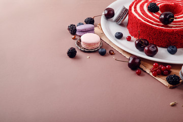 Red velvet cake with berries and macarons. Side view, copy space.