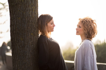 Two beautiful young women in a park at sunset