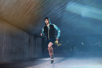 Fit young man jogging in the city at night