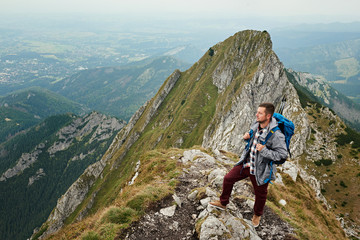 Fototapeta premium Man standing on a peak while trekking in the mountains