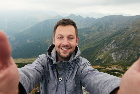 Smiling hiker taking a selfie in front of mountain landscape