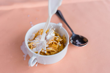 Cornflakes cereal and milk in a clay bowl.