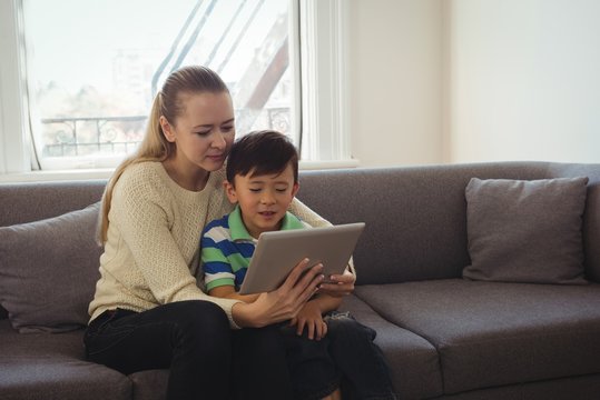 Mother and son using digital tablet in living room