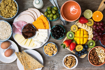 Healthy and various morning breakfast selection:  olives, cereals, ham, cheeses, bread, nuts, fruits, berries, selective focus. Top view