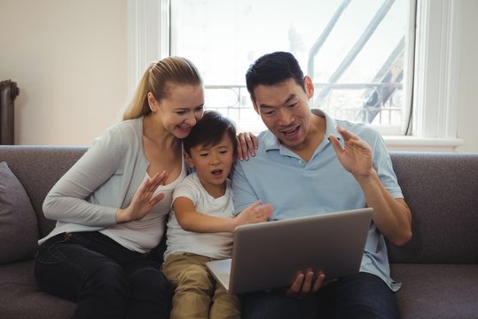 Family having video chat on laptop in living room