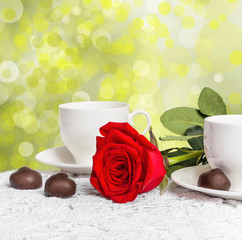 Beautiful red rose and cup of hot tea with chocolate