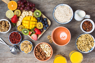 Fototapeta na wymiar Healthy and various morning breakfast selection: cereals, nuts, orange juice, fruits, berries, selective focus. Top view