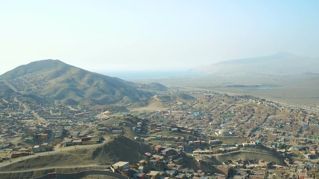 Ventanilla Peru Aerial v5 Flying low over urban poverty hillside housing area panning down.