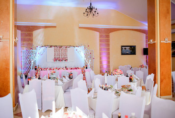 Cosy restaurant decorated in white and pink colors for wedding dinner