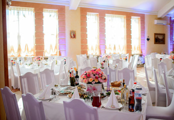 Warm daylight illuminates dinner tables and chairs decorated with white cloth