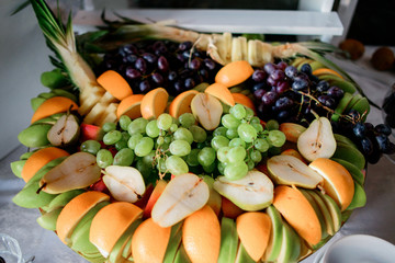 Sliced oranges, pears, apples and grape served on large dish