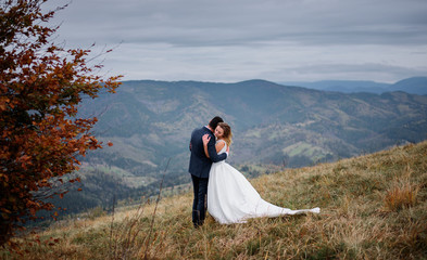 The lovely couple in love embracing and standing on the field