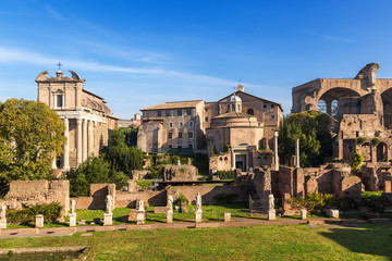 Fototapeta na wymiar Rome, Italy. In foreground - ruins of portico with statues of House of Vestals. In background: Temple of Antoninus and Faustina (141 AD), Temple of Romulus (307 AD), Basilica of Maxentius, 308 AD