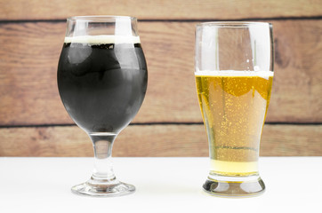 Glasses Of Dark And Light Beers On White Table And Wooden Background