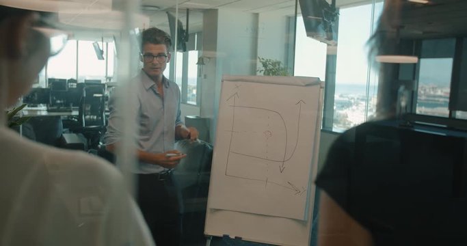 Manager explaining a graph on flipchart to his colleagues. Businessman showing status of project on flipchart.