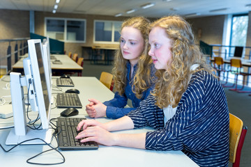 Two dutch students working on computer in school