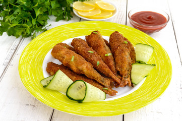 Deep frying small fish capelin on a plate on white wooden background.