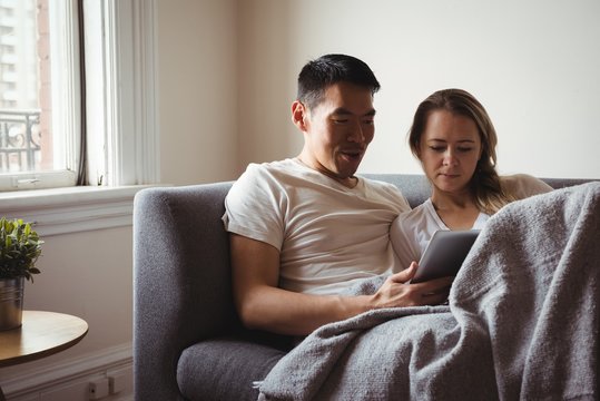 Couple using digital tablet in living room