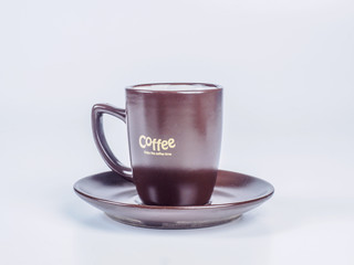 Close up dark brown coffee cup standing on a saucer isolated on white background. Side view.