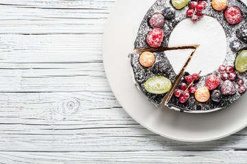 chocolate berry cake on plate over white wooden background