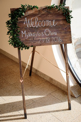 Wooden board with lettering 'Welcome Mykhaylo & Olena. 29.09.2016' stand before the entrance