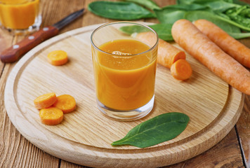 Fresh carrot juice in a glass on a wooden table