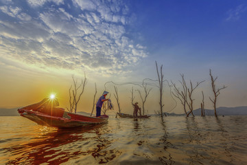 fisherman on the wooden boats, catching fish in the lake at sunset
