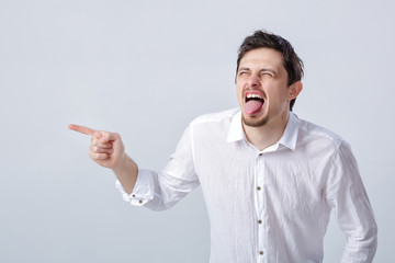 portrait of young man with dark hair in shirt shows up and laugh
