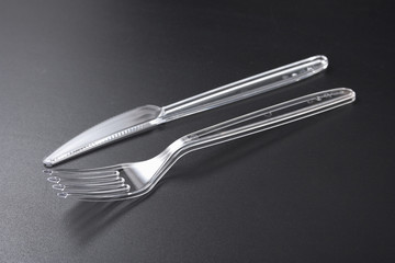 disposable plastic tableware. fork and knife on black background.