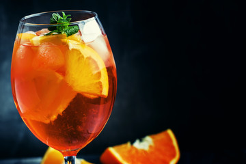 Summer cocktail aperitif with orange bitter, fruit, ice and soda in tall glass, gray-silver...