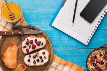 White bowl full of healthy oatmeal, with banana, milk, and dry bread breakfast.