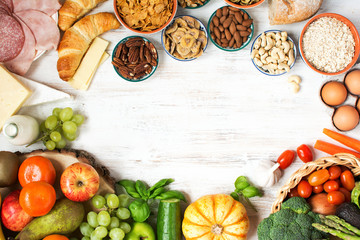 Variety of fruits and vegetables, nuts, cereals, ham, cheese on the white wooden table, top view, selecitve focus