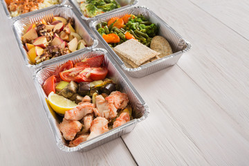 Healthy food take away in foil boxes on wood background