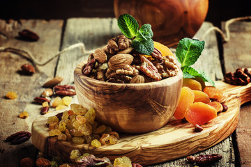 Raisins, dried apricots and assorted nut in a wooden bowl, selective focus