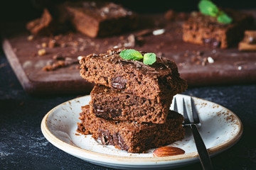 Brownies with chocolate decorated with mint leaf on a dessert plate, closeup view